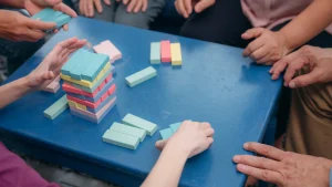 Detail rukou skládajících barevné dílky na modrém stole
