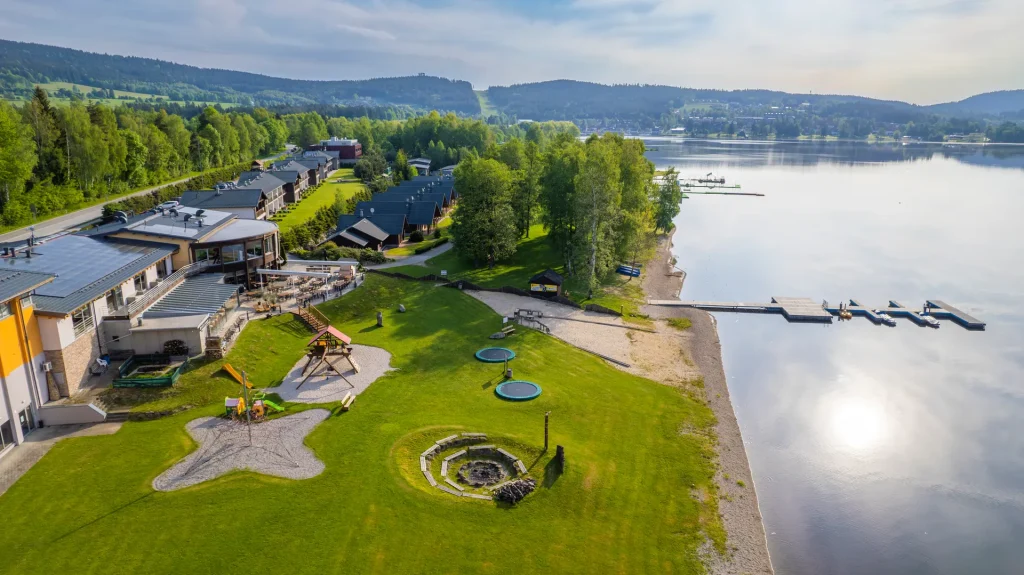 Amenity Hotel & Resort Lipno – Areál resortu s hřištěm, pláží a molem u přehrady Lipno z výšky