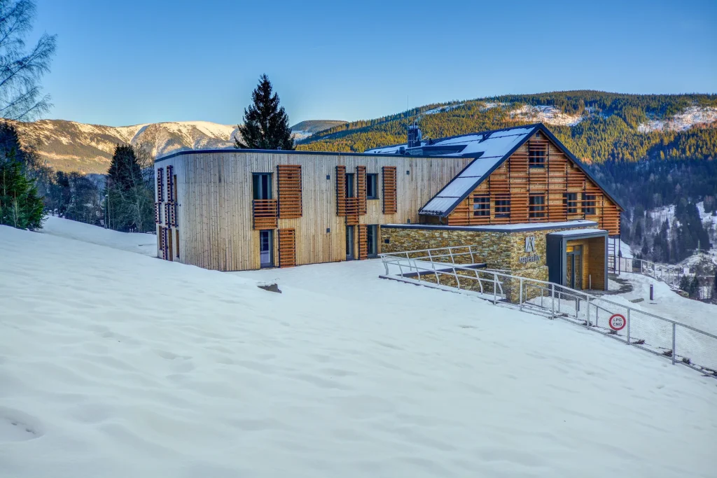 Amenity Hotel & Resort Špindlerův Mlýn – Hotel under snow with mountains in the background