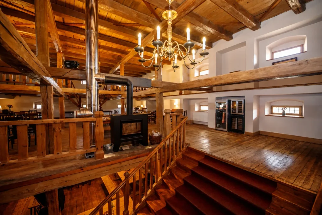 Dvůr Pecínov – Dřevěný interiér restaurace s galerií a kamny