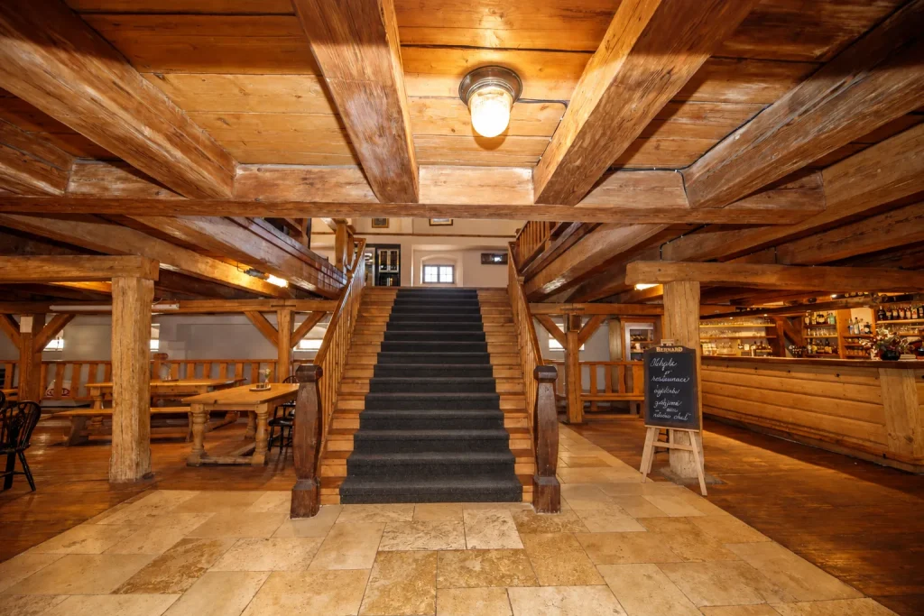 Dvůr Pecínov – Vstup do restaurace s dřevěným schodištěm a barem