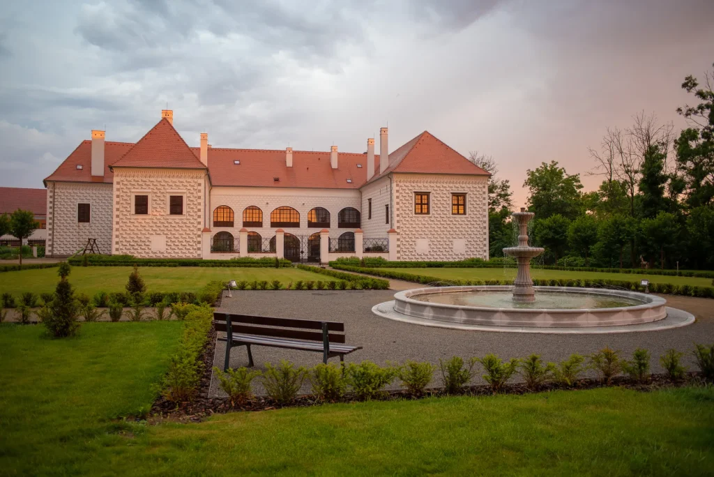 Hotel Chateau Valeč – Chateau front and park with a fountain at sunset