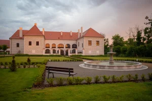 Průčelí zámku a park s fontánou při západu slunce